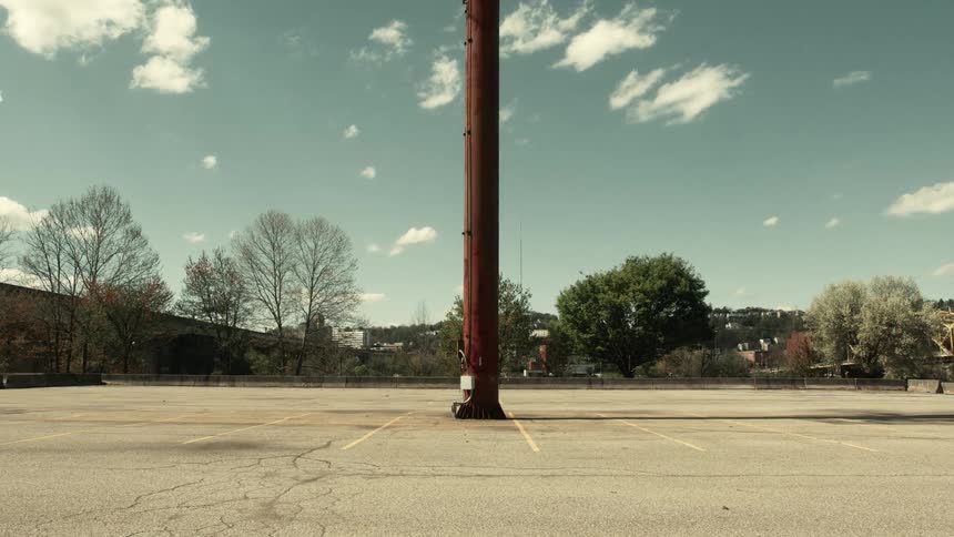 Red tower in the center of an empty parking lot with faded yellow parking lines under a clear blue sky