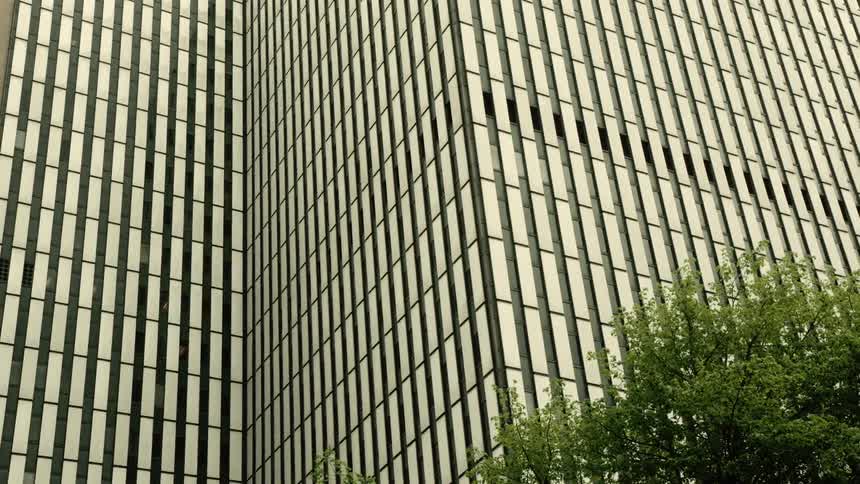 A modern skyscraper with a grid of windows reflects the overcast sky