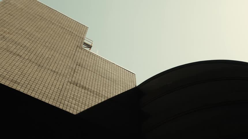 A modern building with a gridlike facade composed of square panels stands against a clear sky