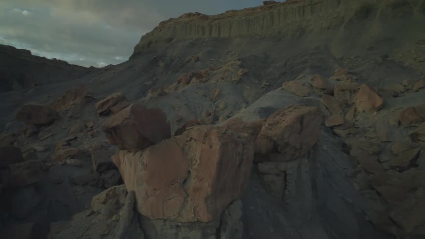 Aerial panorama of rocky and desert mountains with a person riding a mountain bike towards the peak
