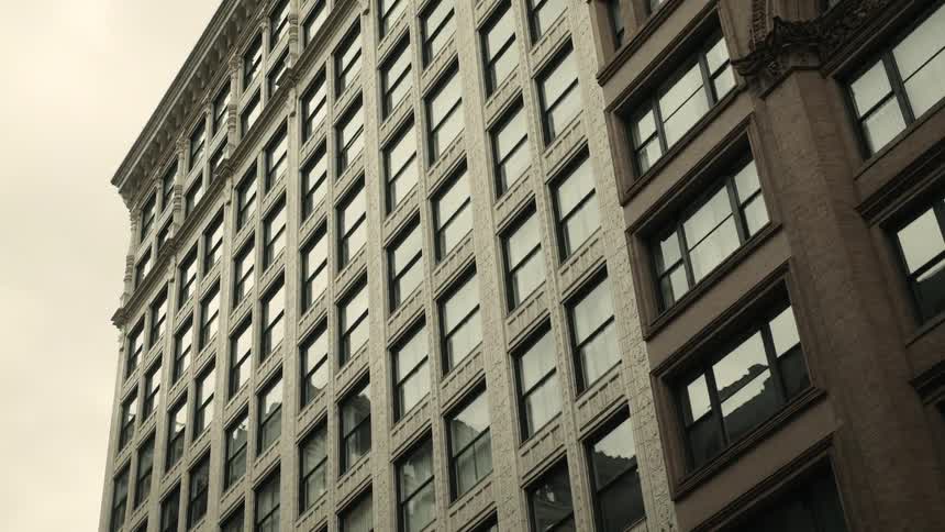 Rows of windows on high rise building reflect the sky and nearby buildings
