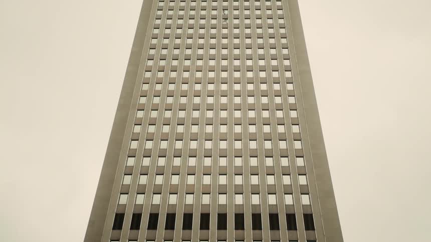 Tall building seen from below highlighting its verticality and the repetitive pattern of windows against a clear sky