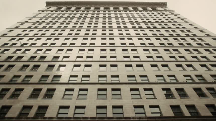 A bird flies by a tall office style structure in a city