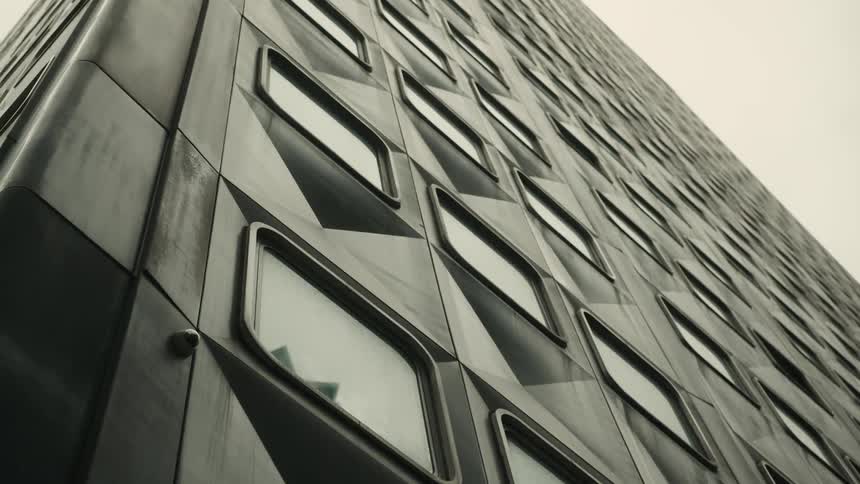 Upward view of patterned windows in a modern building against a cloudy background