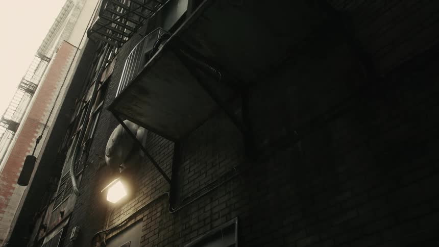 The alley is dark by the apartment building