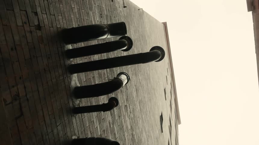 Upward view of a brick wall with black pipes