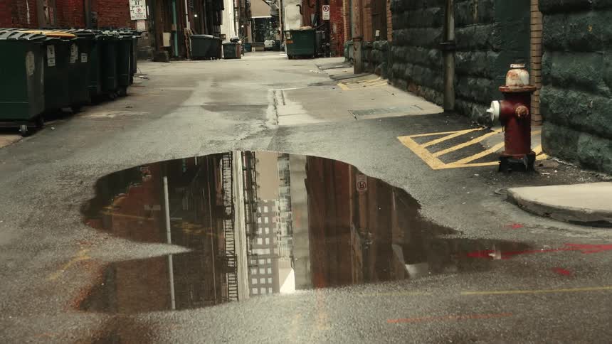 Puddle of water in an alley that reflects surrounding buildings