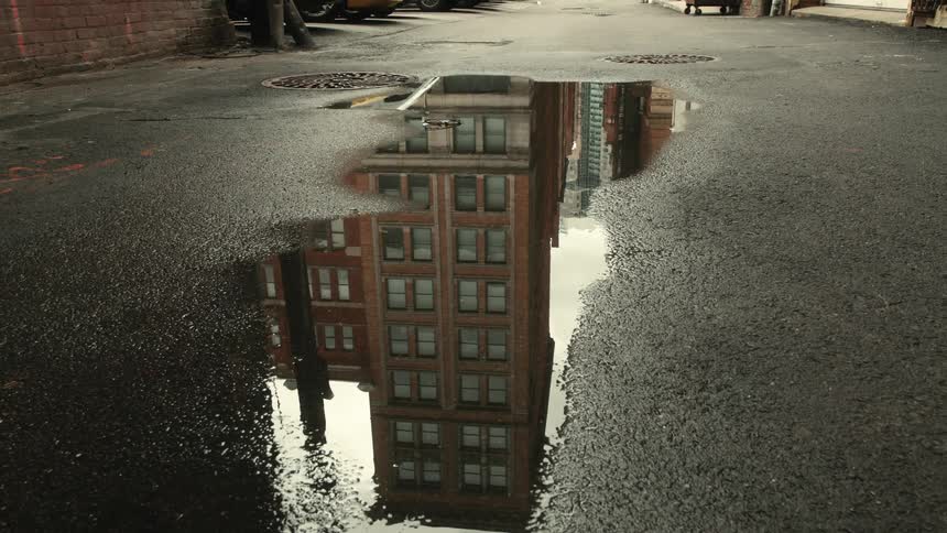 Reflection of buildings in a puddle on an empty street