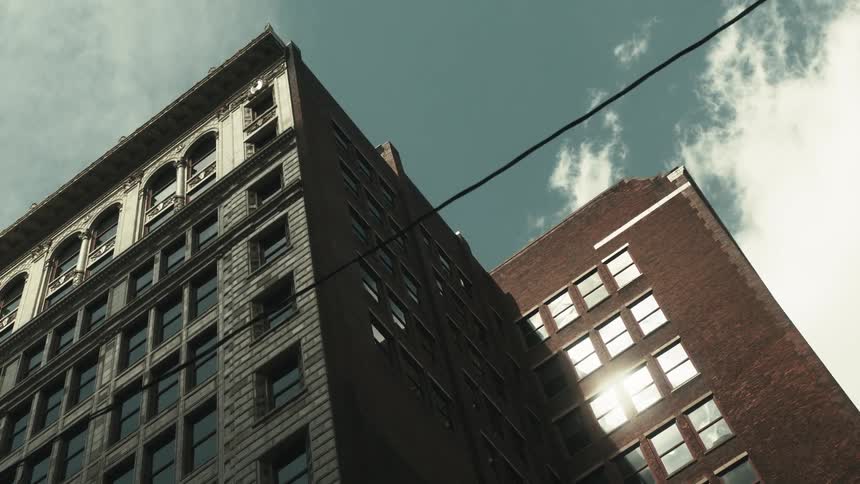Mid rise office building reflects the glaring sunlight while towering over a power line on a cloudy day