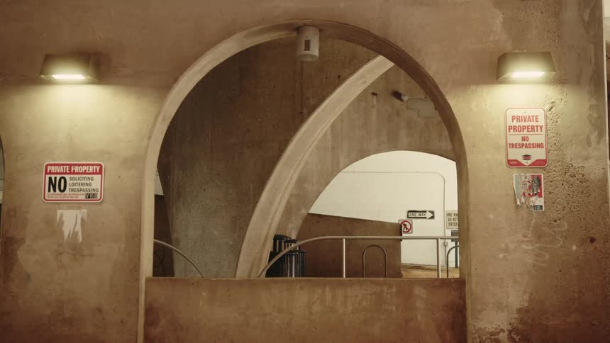 Concrete interior with arches and a staircase marked by several plaques