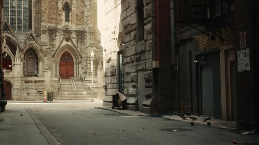Birds pick at the sidewalk near a bin and a church in a city