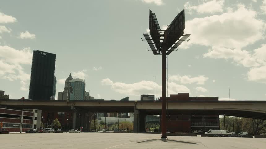 Billboards in front of an overpass and metropolis under a partly cloudy sky