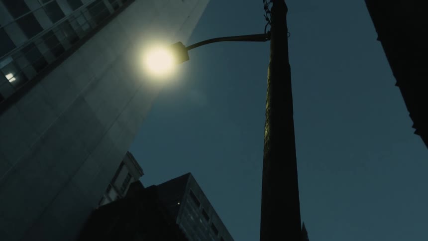 A low angle view of a streetlight in the dark city streets at night
