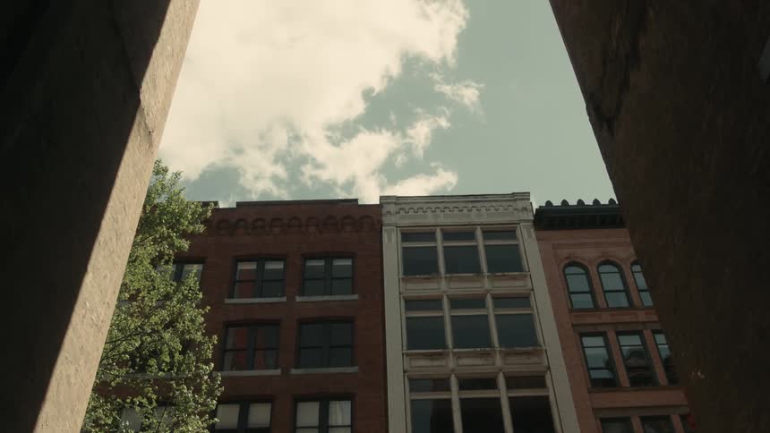 Narrow alley with urban buildings in the background on a partly cloudy day