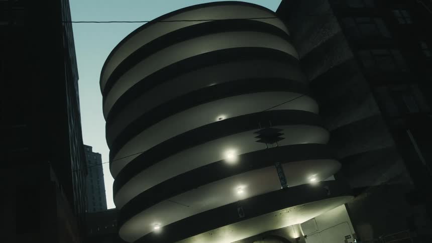 Round building illuminated at night in a metropolis
