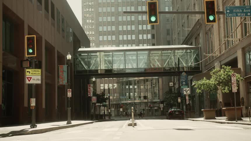 Traffic signal shows green on street leading under a downtown pedestrian bridge