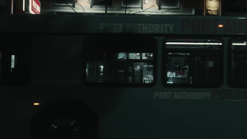 Facade of a store at night with cars and buses passing in front