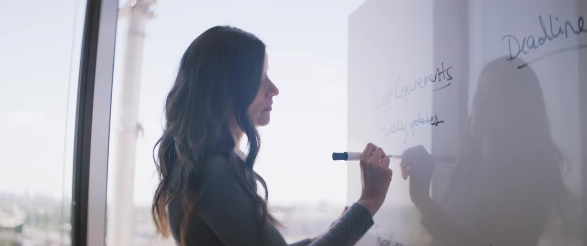 A business woman writes words on a whiteboard in an office