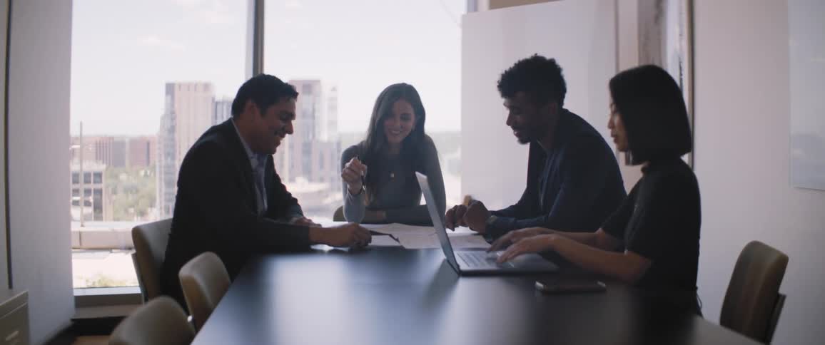 A group of coworkers seated around a table in a meeting room in the city