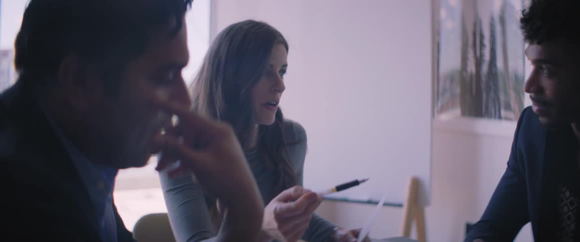 Three employees are sitting in a conference room and collaborating