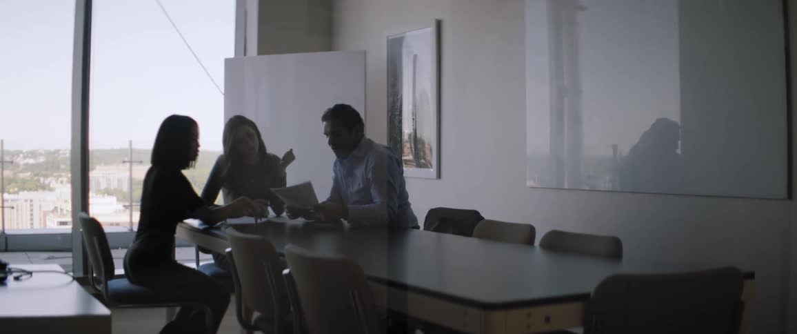 Three individuals sitting around a conference table in a room
