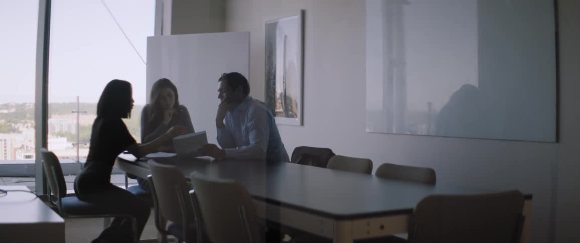 Three individuals in an office environment engaged in an argument