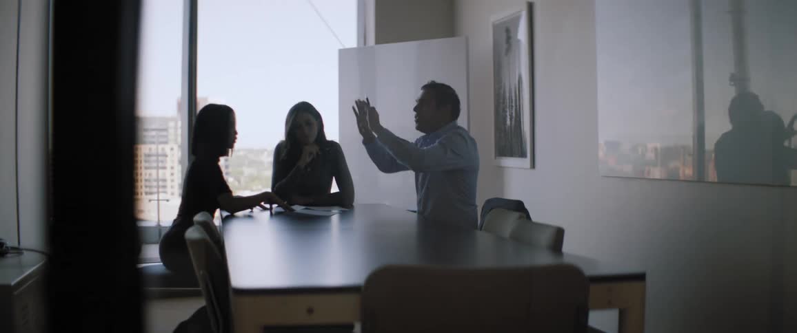 A meeting of three people around an office table