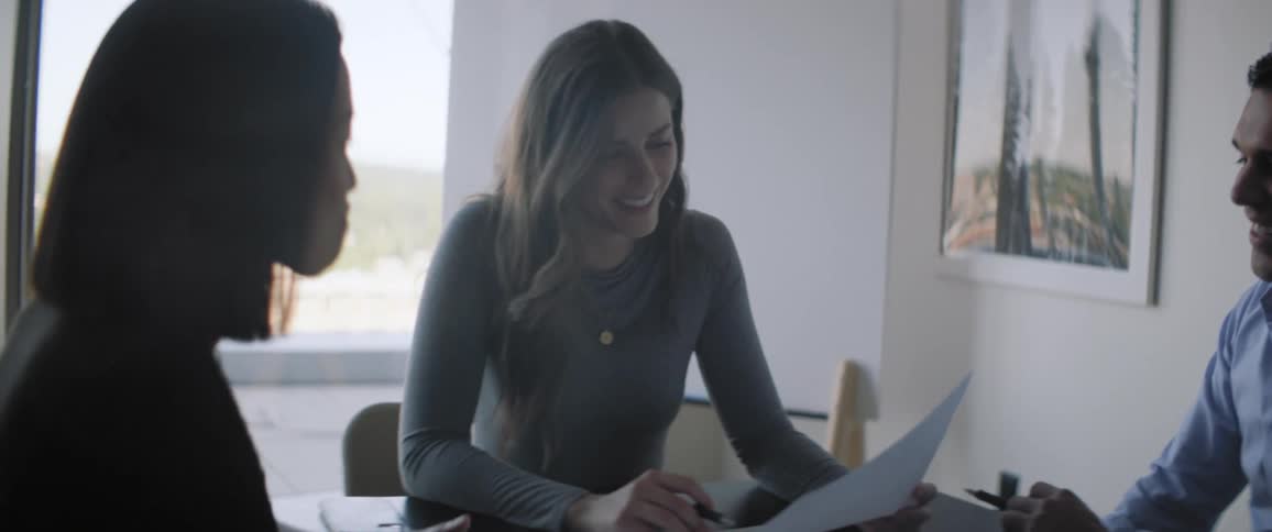 Man and two women sitting at an office table smiling and talking
