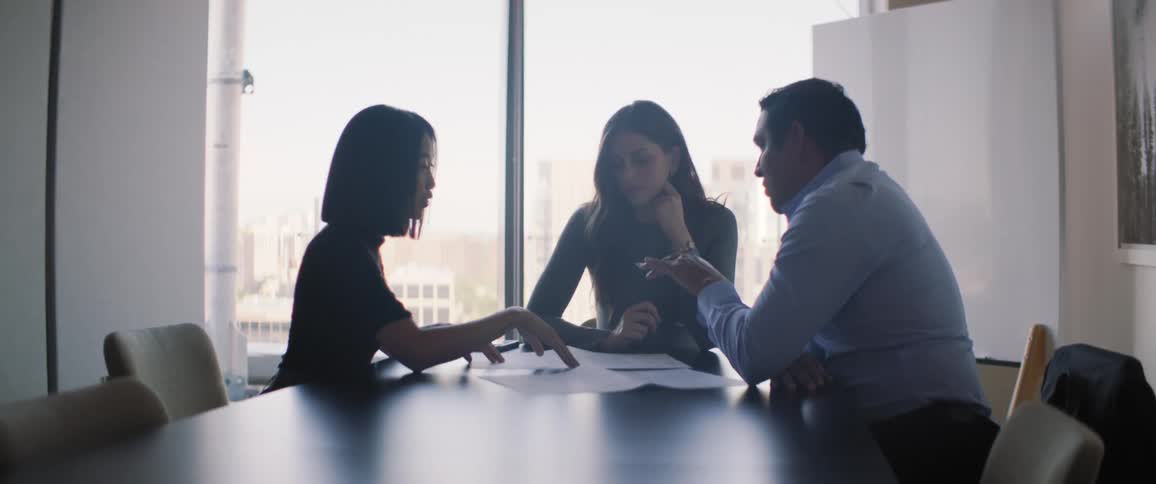 Meeting of three people sitting at an office table debating