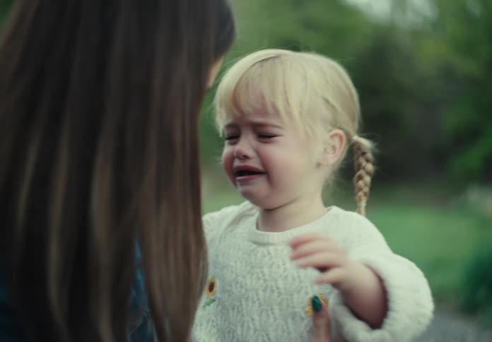A mother standing on a trail outdoors consoling her daughter crying baby daughter
