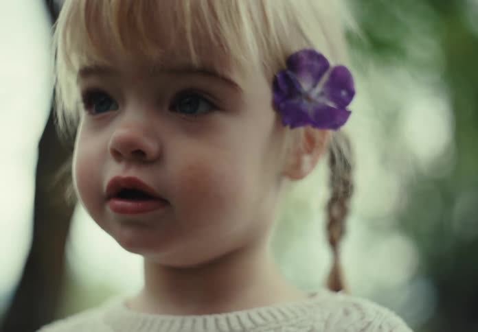 Portrait of a little blonde girl with a flower that is placed in her ear