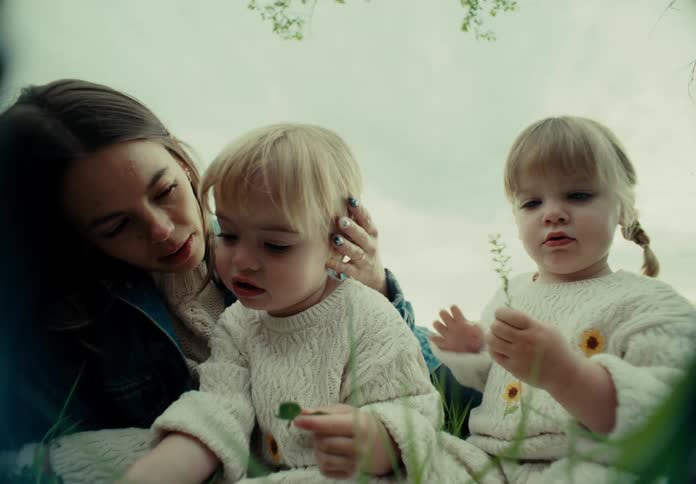 Mother sitting in the garden with her two little twin daughters