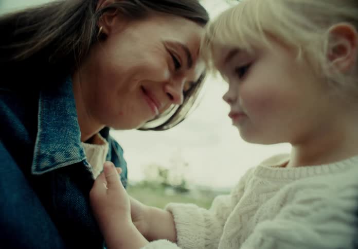 Smiling mother and daughter sitting in a field