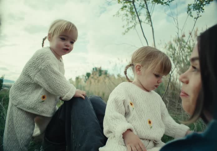 Mother sitting in a stabbed field with her two young twin daughters