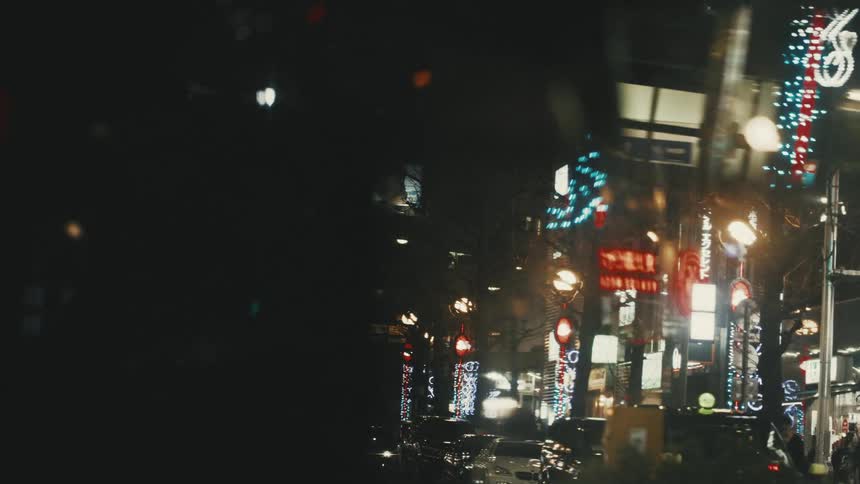 A nighttime street scene with illuminated signs traffic lights and vehicles