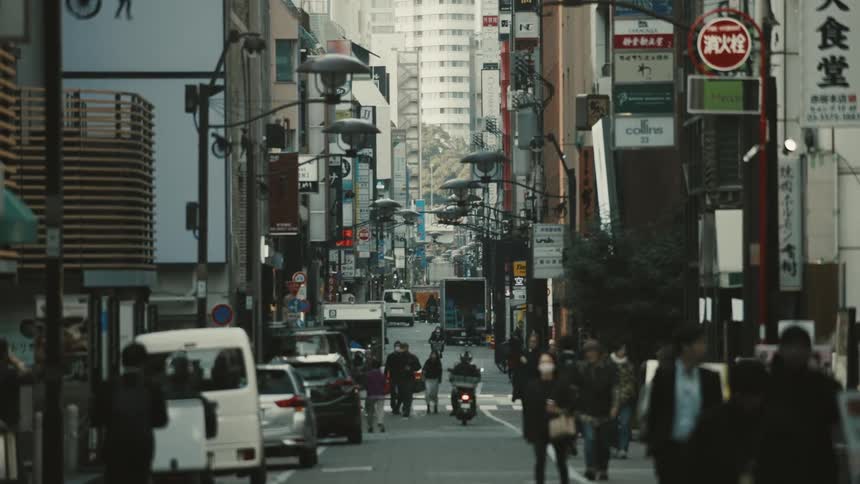 Narrow street with pedestrians and vehicle traffic in a city with large buildings in a metropolis