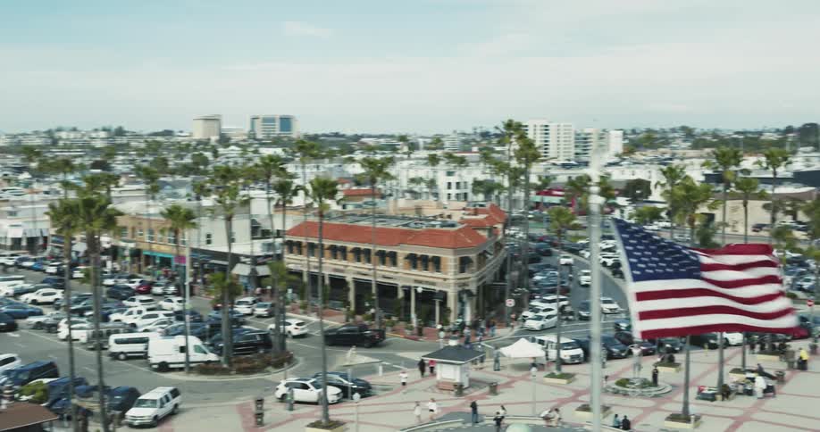 Aerial view of a busy urban area during the day with a large american flag highlighted and the edge of a beach