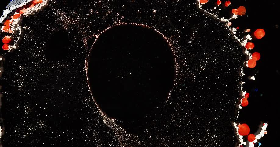 A liquid that expands to create a void ringed with bright orange blobs