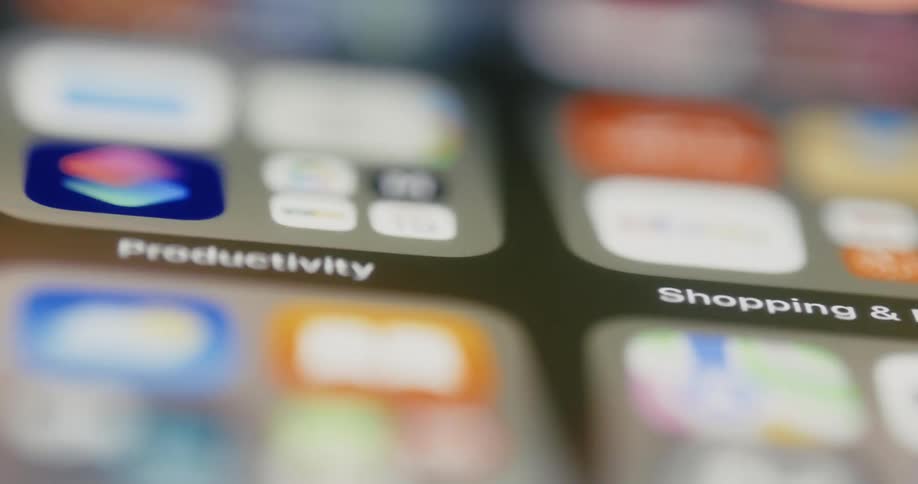 A person scrolls through apps on a smartphone and touches a few of them