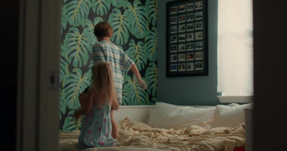 Little boy and girl playing holding hands jumping on the bed