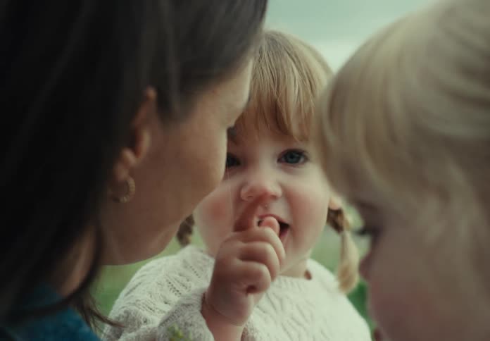 Smiling mother next to her two little daughters in a garden