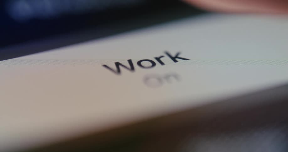 Close up of a finger pressing a digital button with the word work on the screen