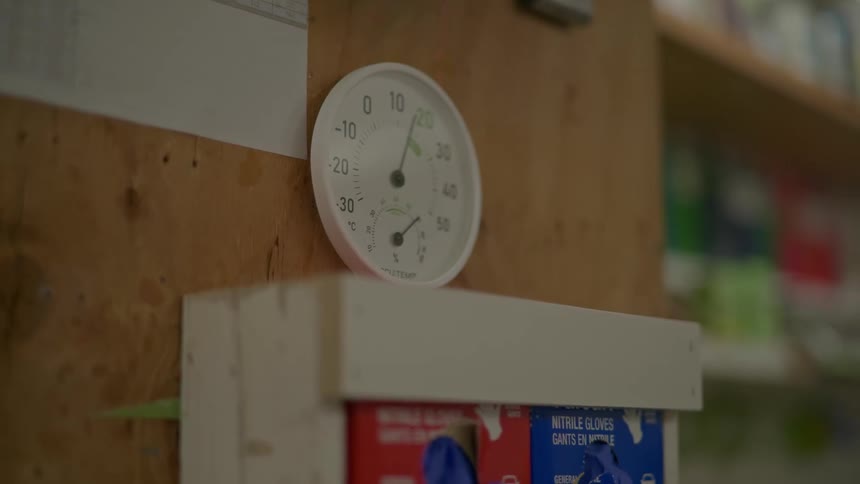 Round thermometer sitting on a glove dispenser inside a pharmacy