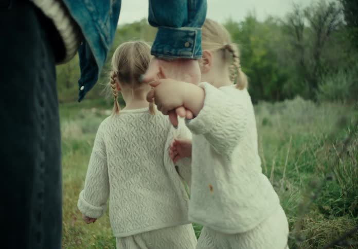 Mother walking on the grass with her two little daughters
