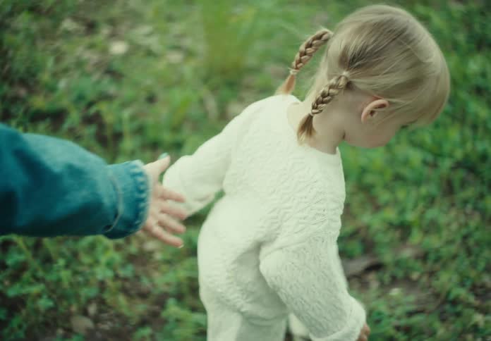 Little girl walking on the grass next to her mother