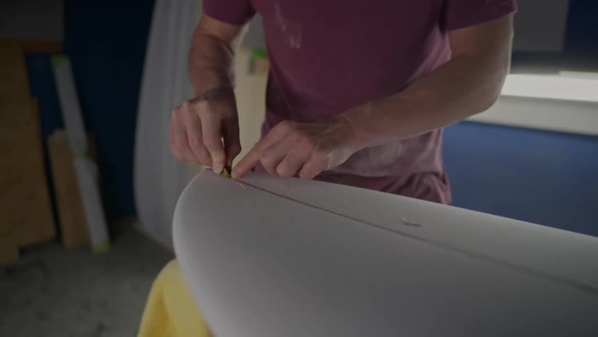 Pair of a mans hands working on a surfboard
