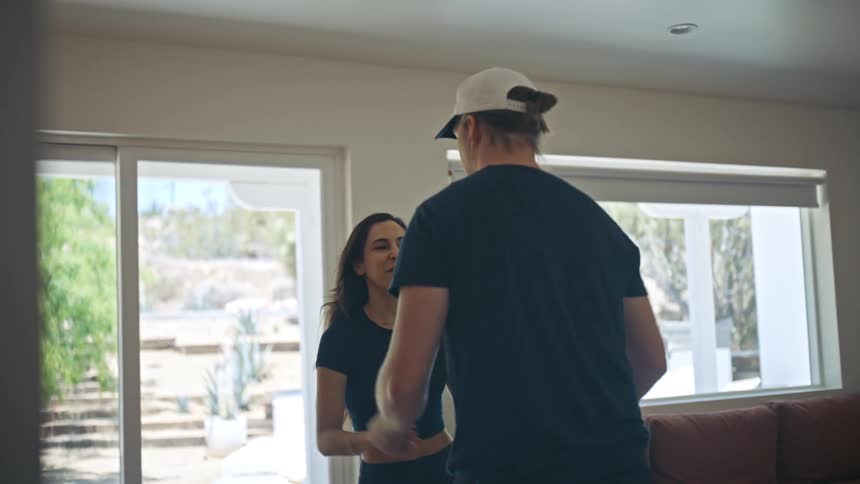 A young couple practicing a dance in the living room at home