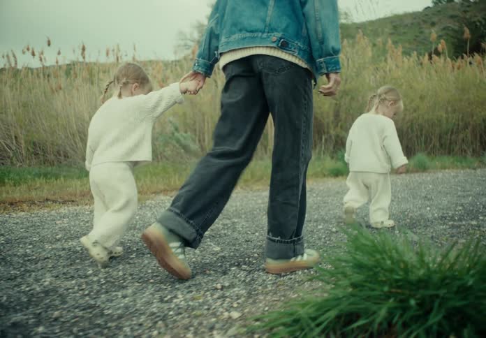 Mother walking with her two little twin daughters on a stone street with greenery around
