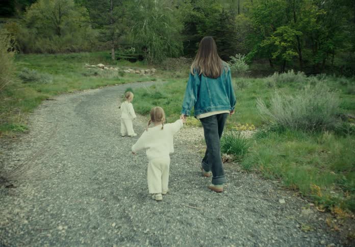 A mother walks down a gravel road with her twin daughters on a spring day