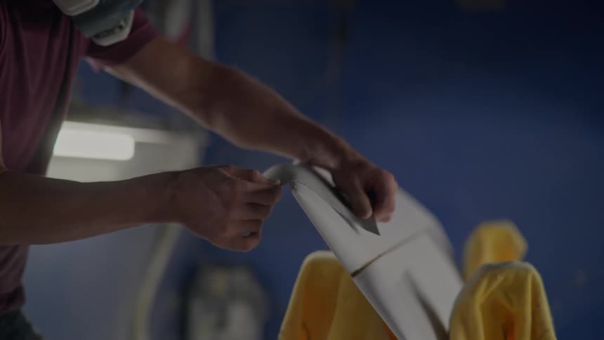 A man gently sands the board with sandpaper